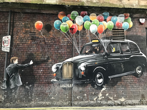 Street Art Of A Taxi Lifted By Balloons With A Person Reaching Out