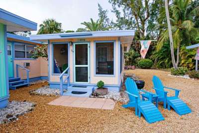 Heron Cottage exterior with screened lanai and adirondack chairs and grill.