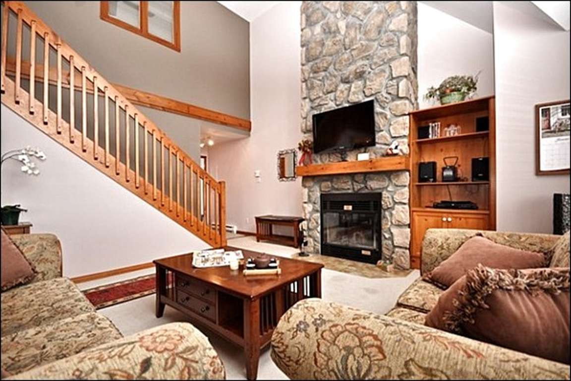 The Living Area Features Large Picturesque Windows and a Cozy Stone Fireplace