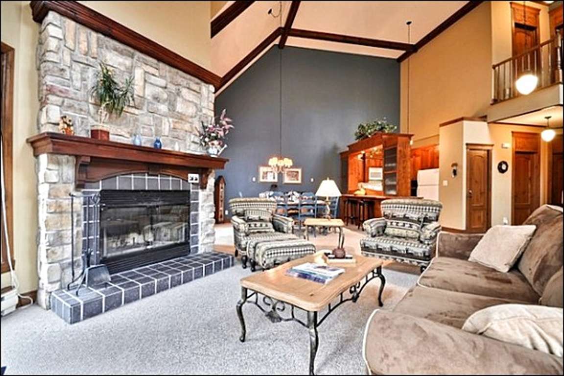 The Living Area Features a Beautiful Stone Fireplace, Large Picturesque Windows, and Cozy Furnishings